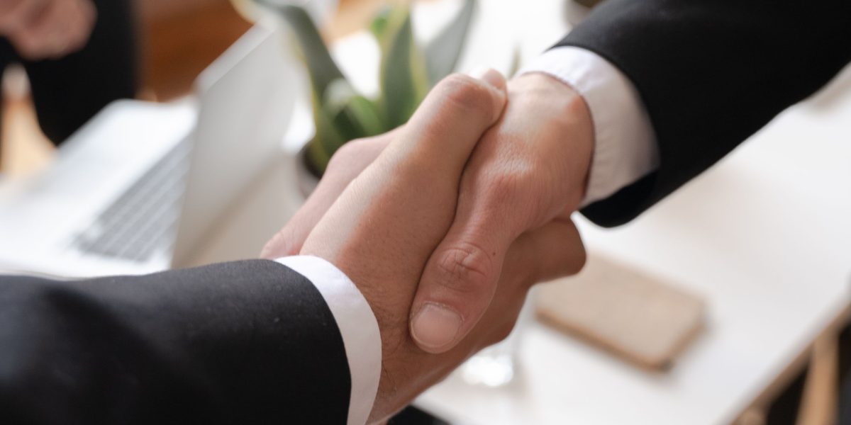 Two professionals shaking hands, symbolizing successful collaboration and stakeholder buy-in during tech implementation.