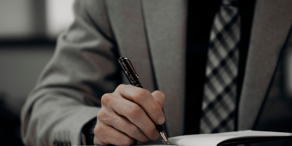 A professional in an office setting, intently writing or drawing on a large notepad, signifying the creation of an action plan for compliance.