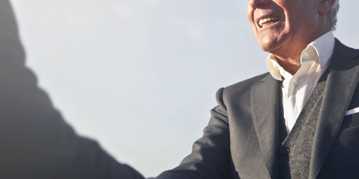 A business leader shaking hands with a legal advisor, symbolizing the practical application of national government powers for client advice and risk management.